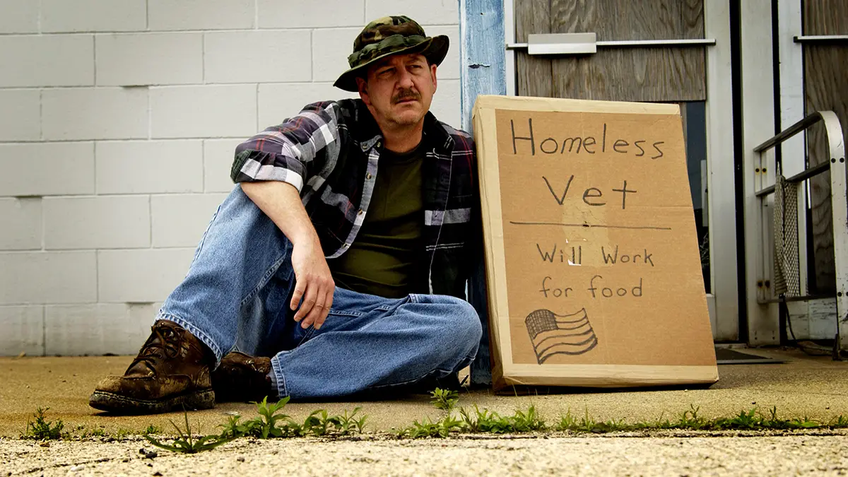 Photo of homeless veteran on street with "Will work for food" sign