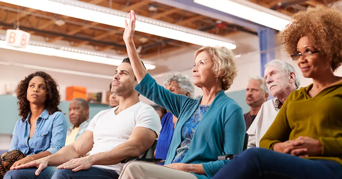 Photo of local residents sitting down to attend a public community meeting - Photo by Adobe Stock