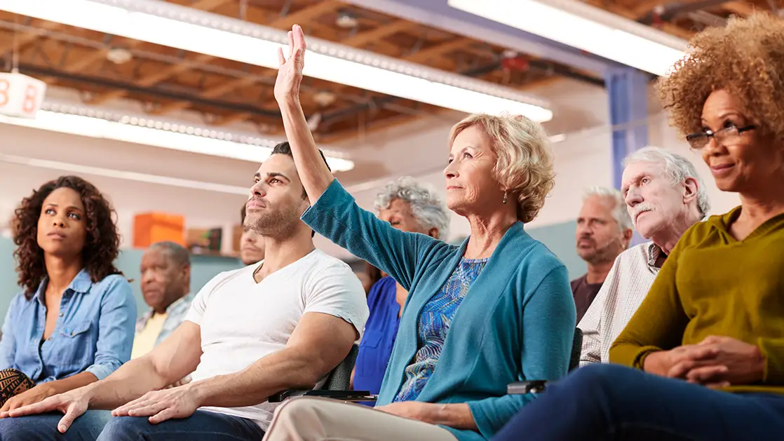 Photo of local residents sitting down to attend a public community meeting - Photo by Adobe Stock