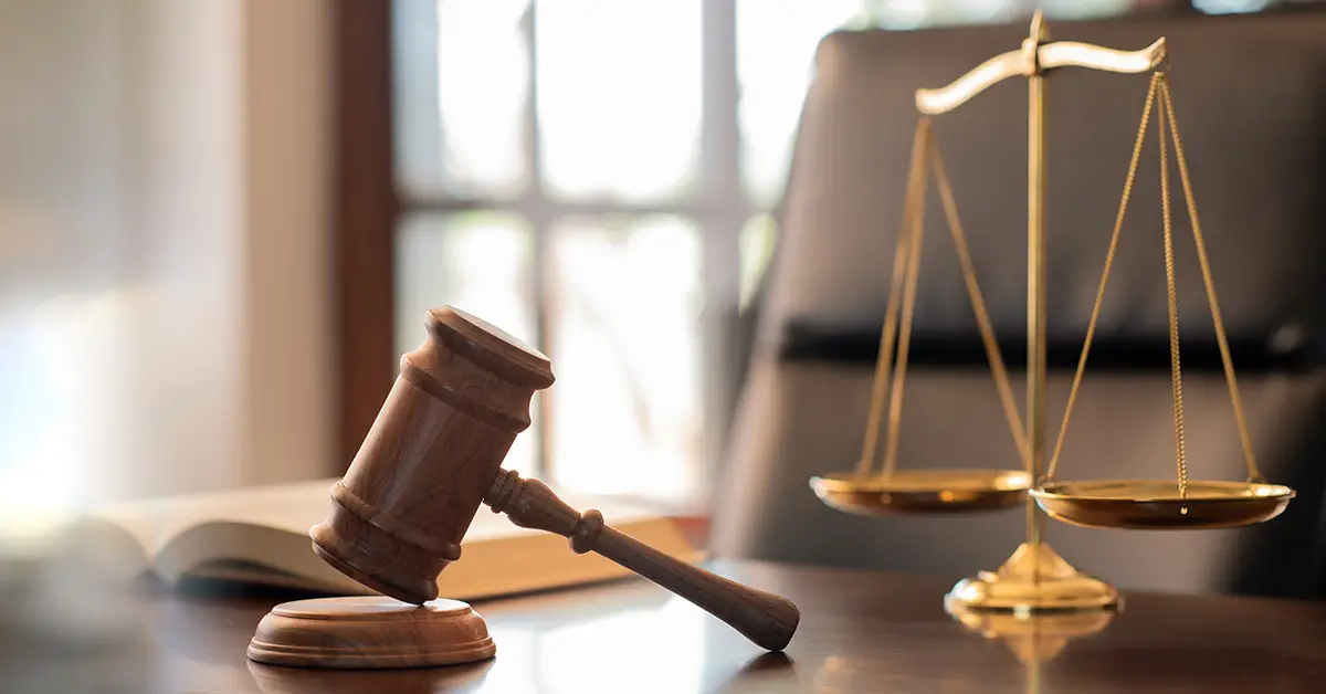 Photo of a gavel on a desk with a law book. Photo by Adobe Stock.