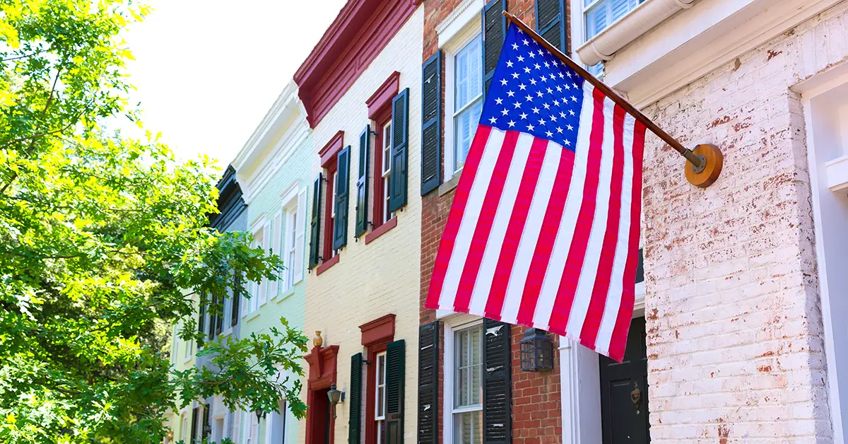 Photo of a U.S. flag mounted on a pole attached to a row of townhomes.