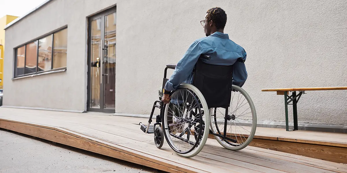 Photo of a man in a wheelchair using a ramp to get to the front door of his home.