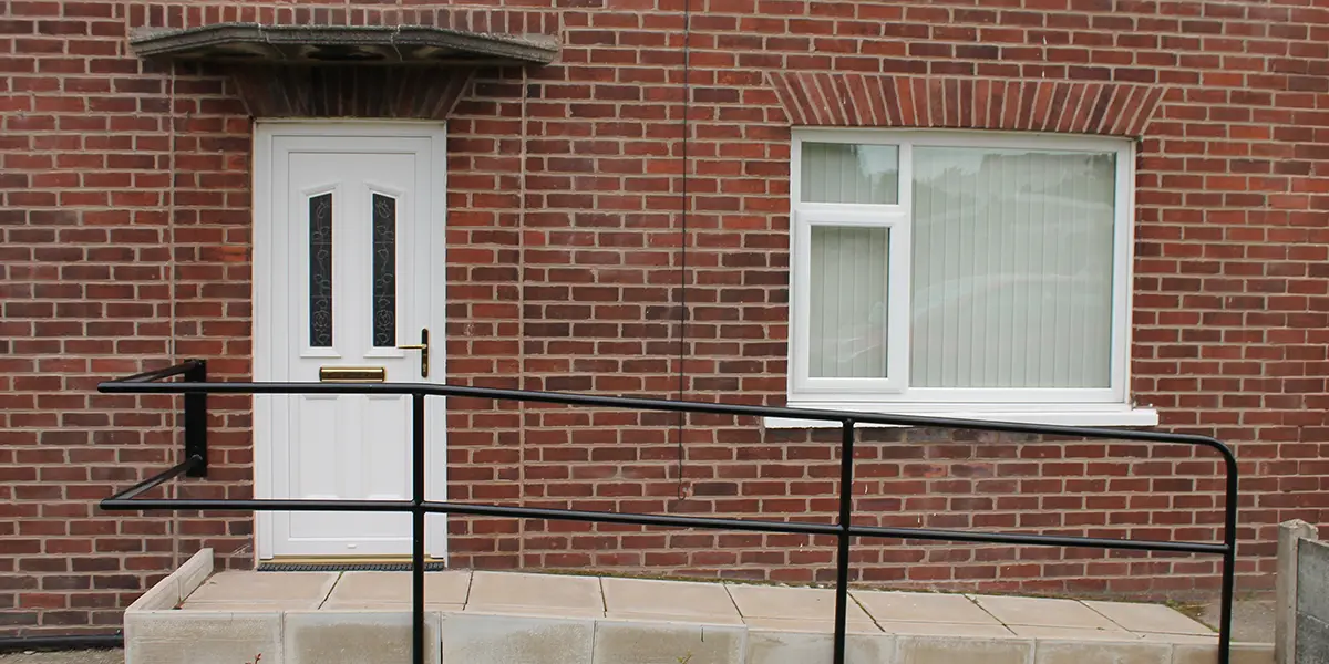 Photo of the front of a home with a brick wall, and an accessible ramp.