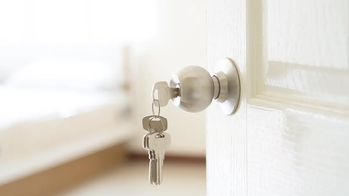 Photo of a key in a doorknob of an open door to a new home.