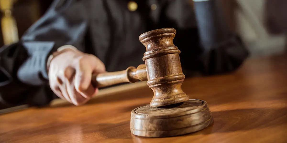 Photo of a judge holding his gavel, and banging it on his table during a court case.