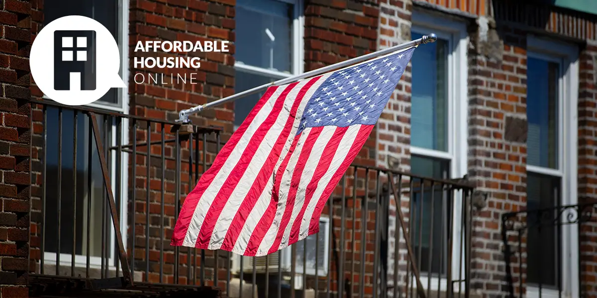 Photo of a city apartment exterior, with a pole flying the Unites States flag.