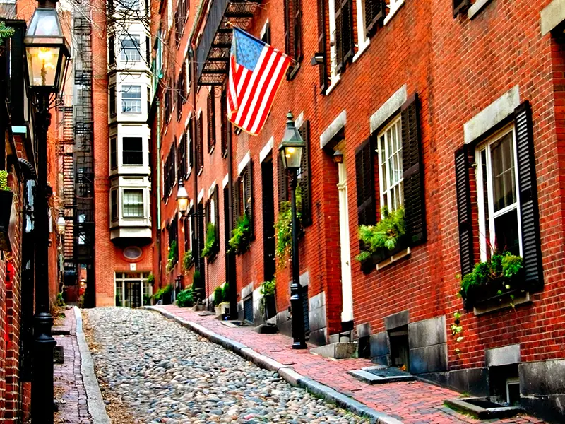 Photo of an urban block of apartments on a city street, with the Unites States flag flying in front of one unit.