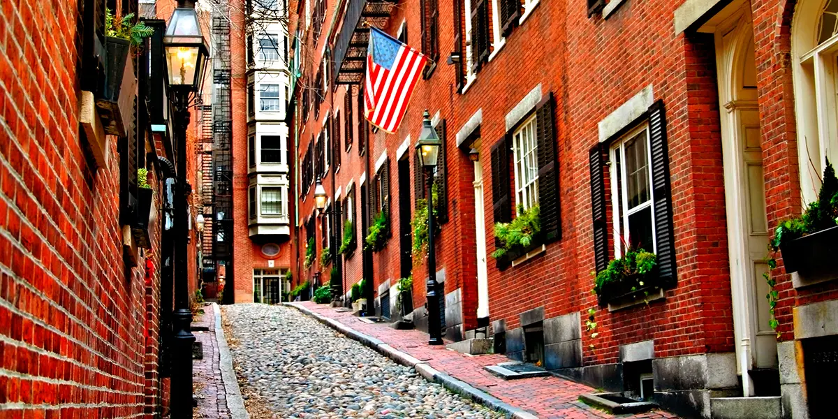 Photo of an urban block of apartments on a city street, with the Unites States flag flying in front of one unit.