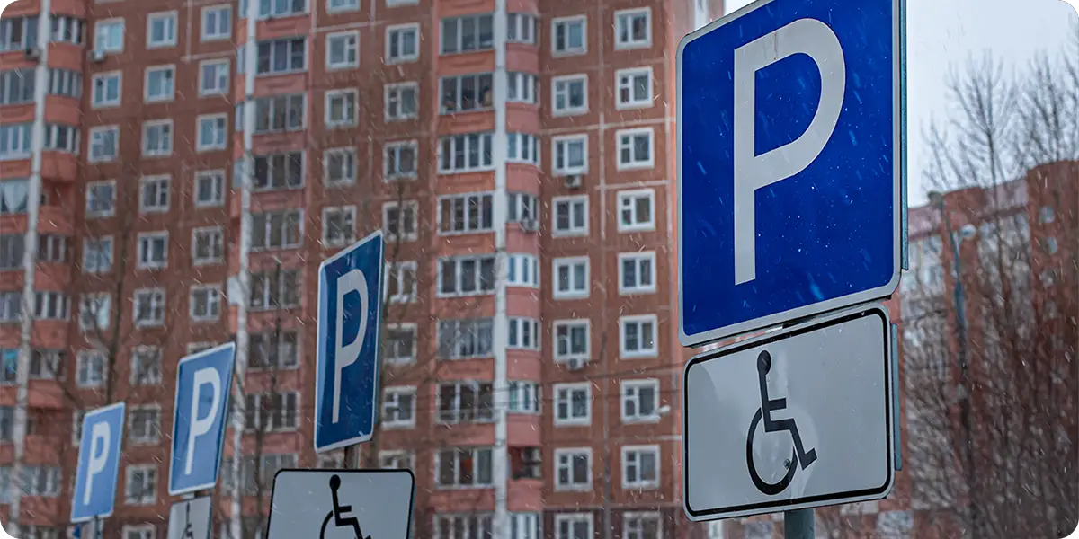 Photo of handicapped parking signs in front of an urban apartment hi rise.
